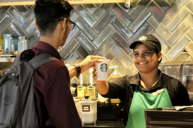 An Indian Starbucks Coffee offers a coffee cup a customer wearing a bag