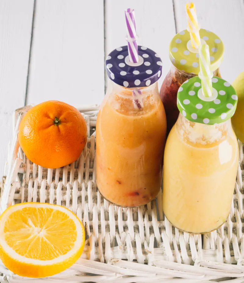 cold coffee bottles with oranges lying around on a table