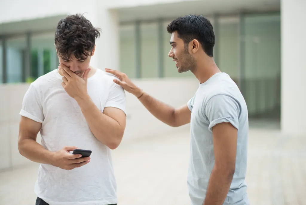 two men standing next to each other, the second one reading his hand out on the shoulder