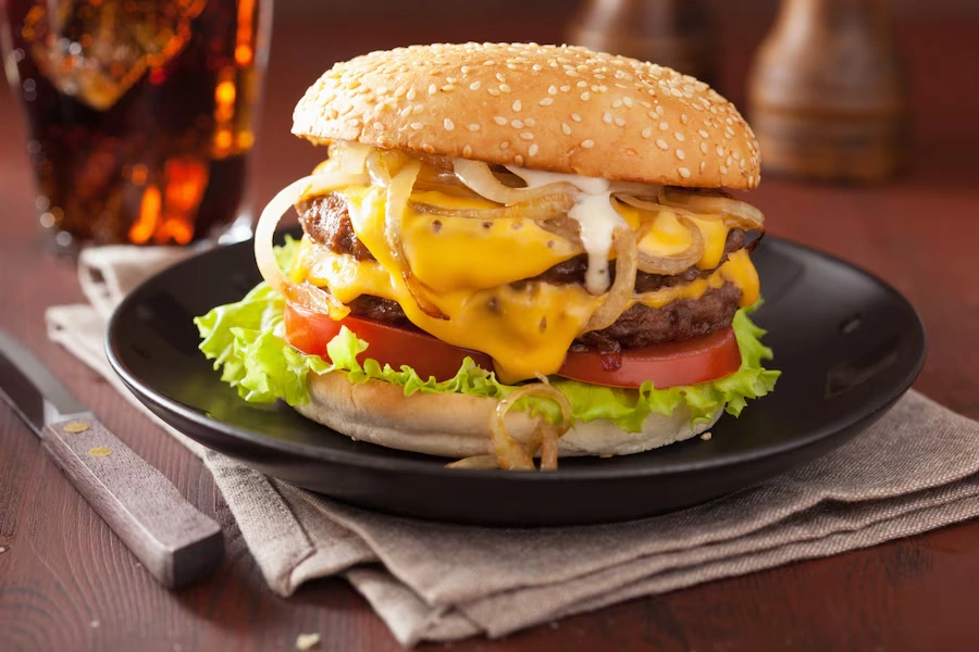 Double cheeseburger with melted cheese, tomato and onion.