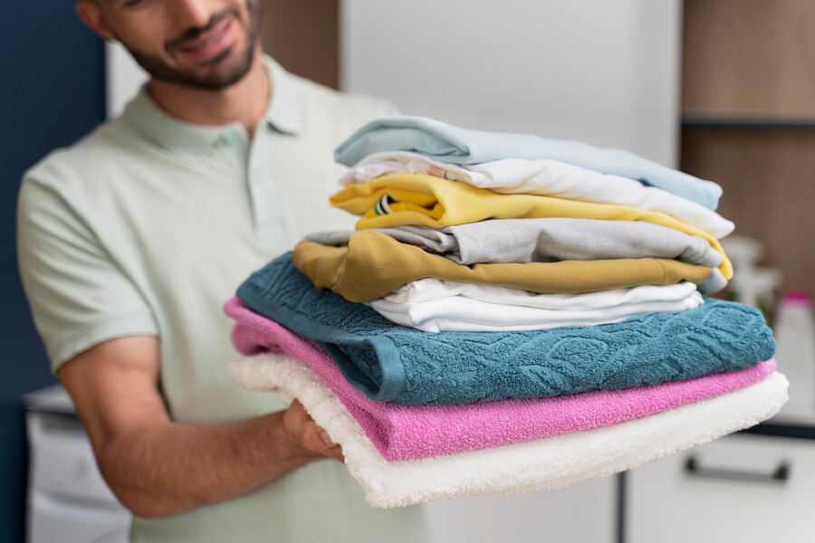 Man holding a pile of clean laundry