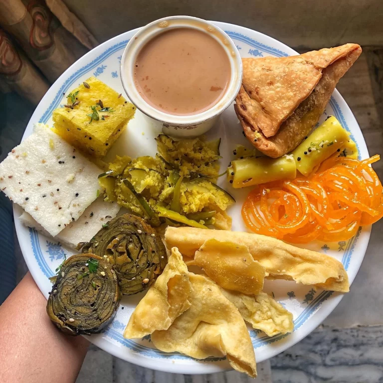 Image of Gujarati street food such as khaman, dhokla, fafda-jalebi, khandvi etc put together on a plate.